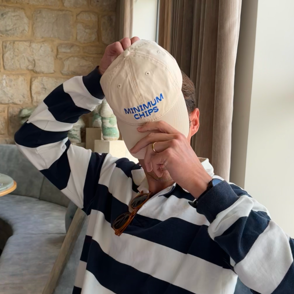 A beige baseball cap with 'MINIMUM CHIPS' embroidered in blue on the front.