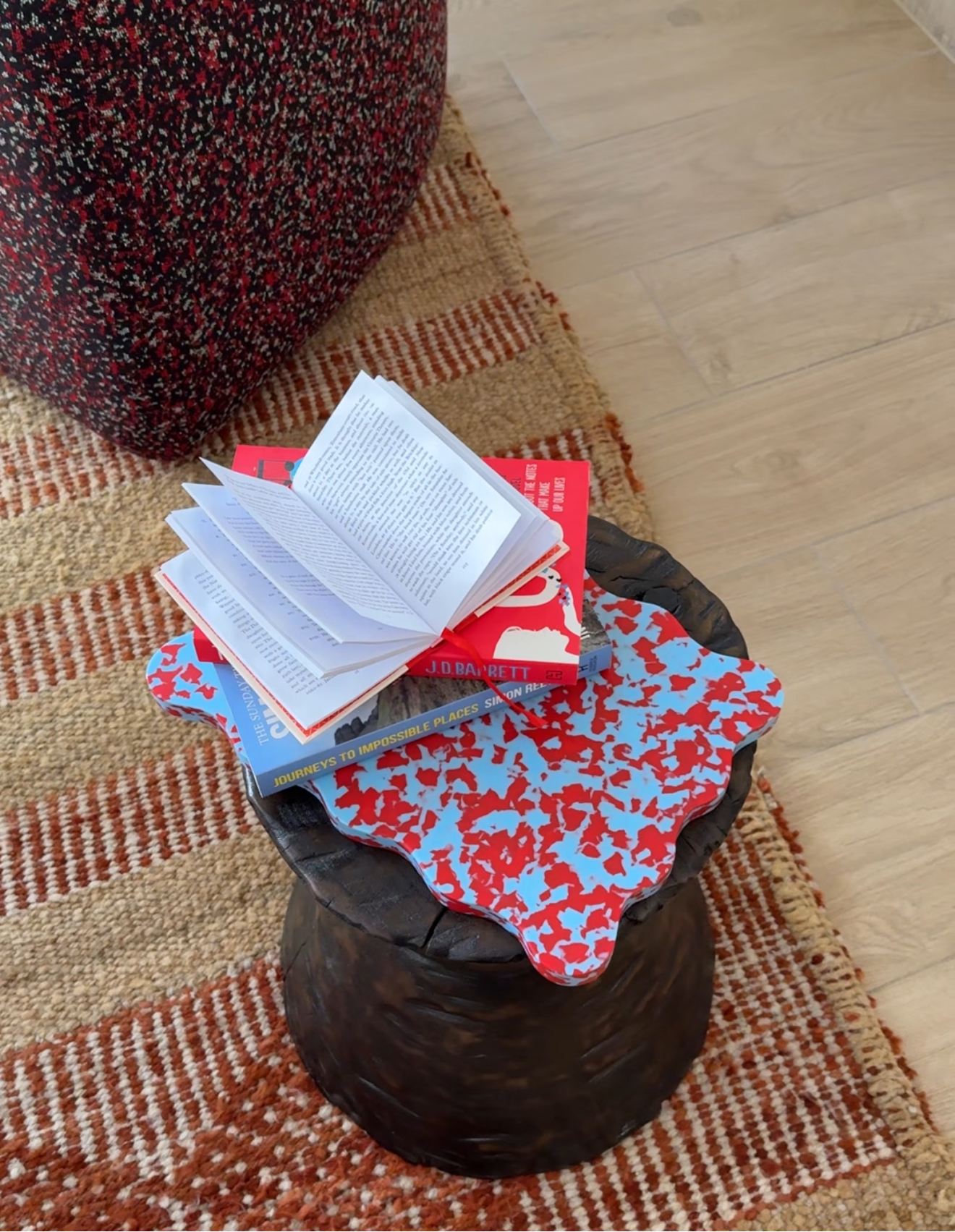 Pastel blue and red wavy, scalloped chopping board on a wooden side table.