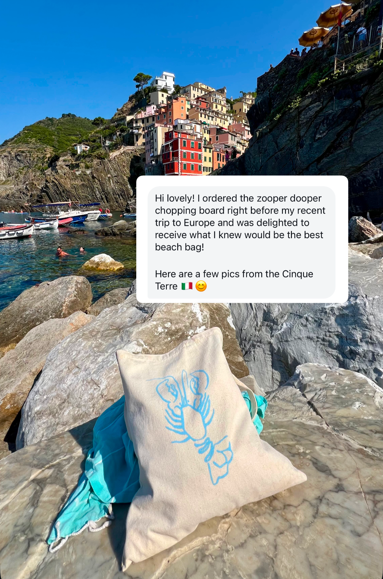 A beige cotton canvas tote bag with long straps, featuring a blue lobster print on a European beach.