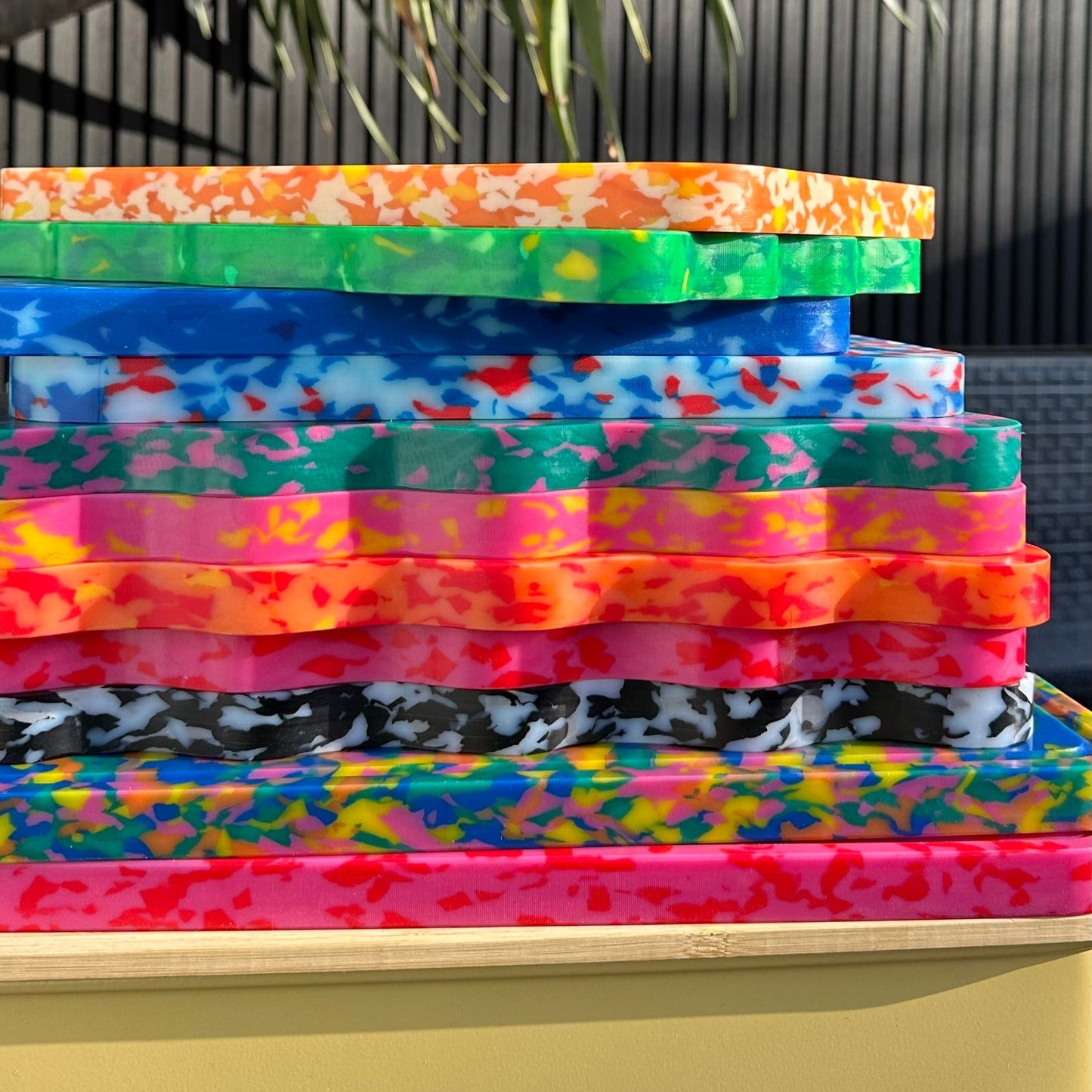 Stack of colourful wavy chopping boards by Pinchy – multicoloured terrazzo-style kitchen boards in sunlight
