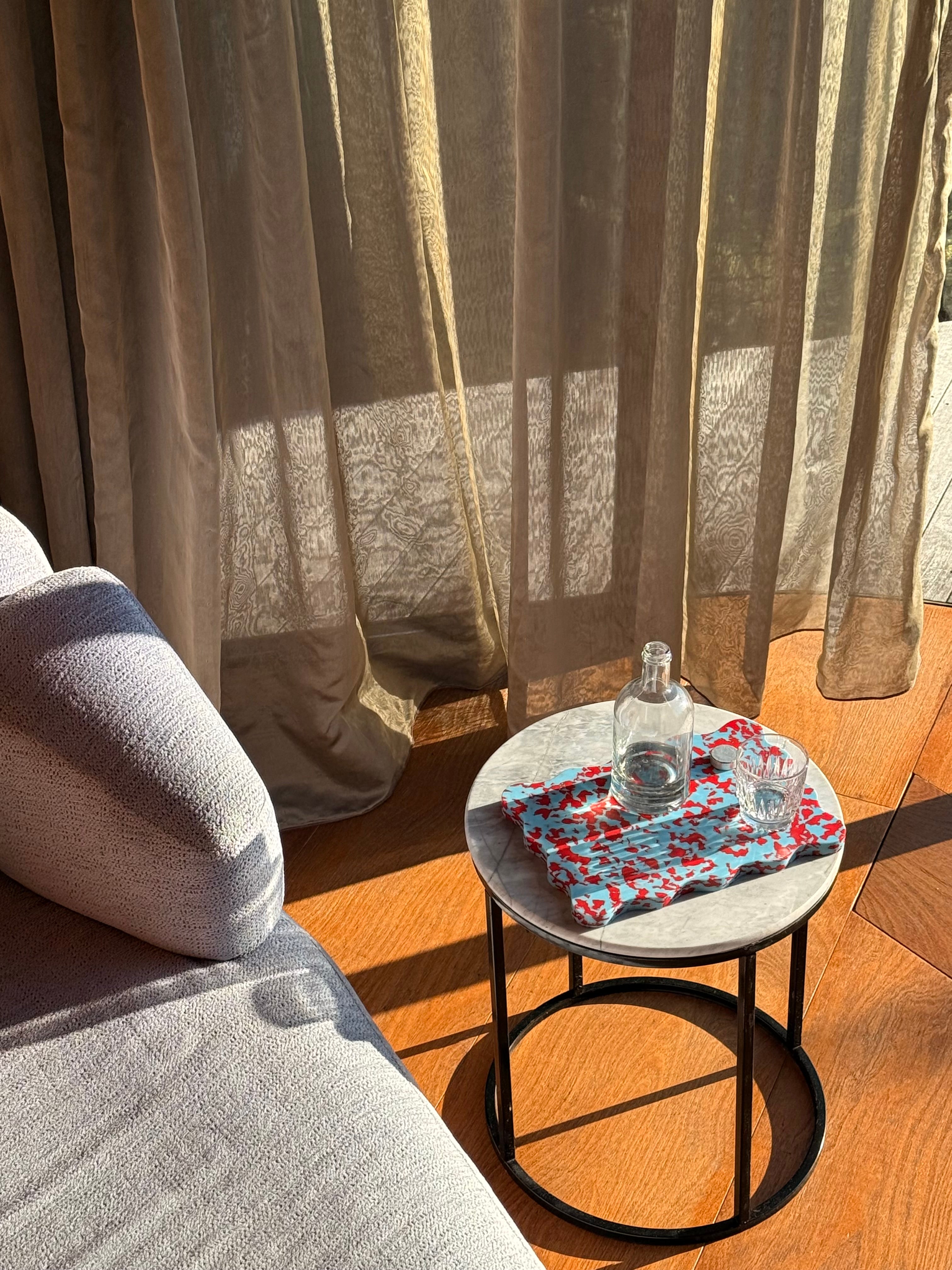 Pastel blue and red wavy scalloped chopping board on a marble bench. 