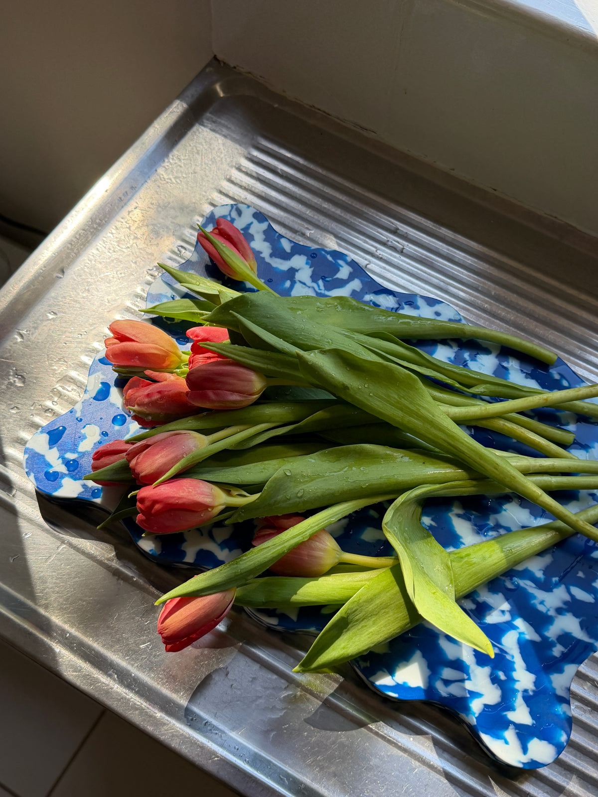 Fresh tulips on a electric blue and white wavy edged chopping board. 