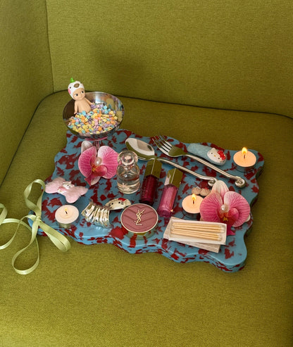 Red and blue cutting board used as a decorative scalloped tray with small items displayed. 